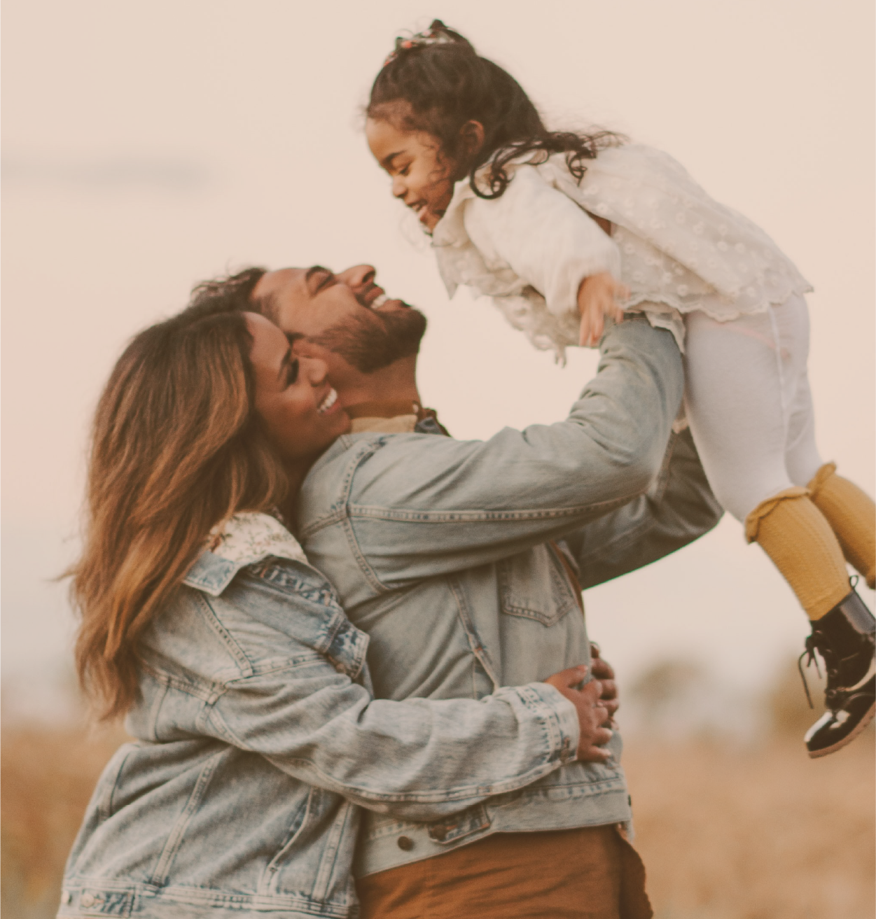 Parents portant leur petite fille en riant en extérieur