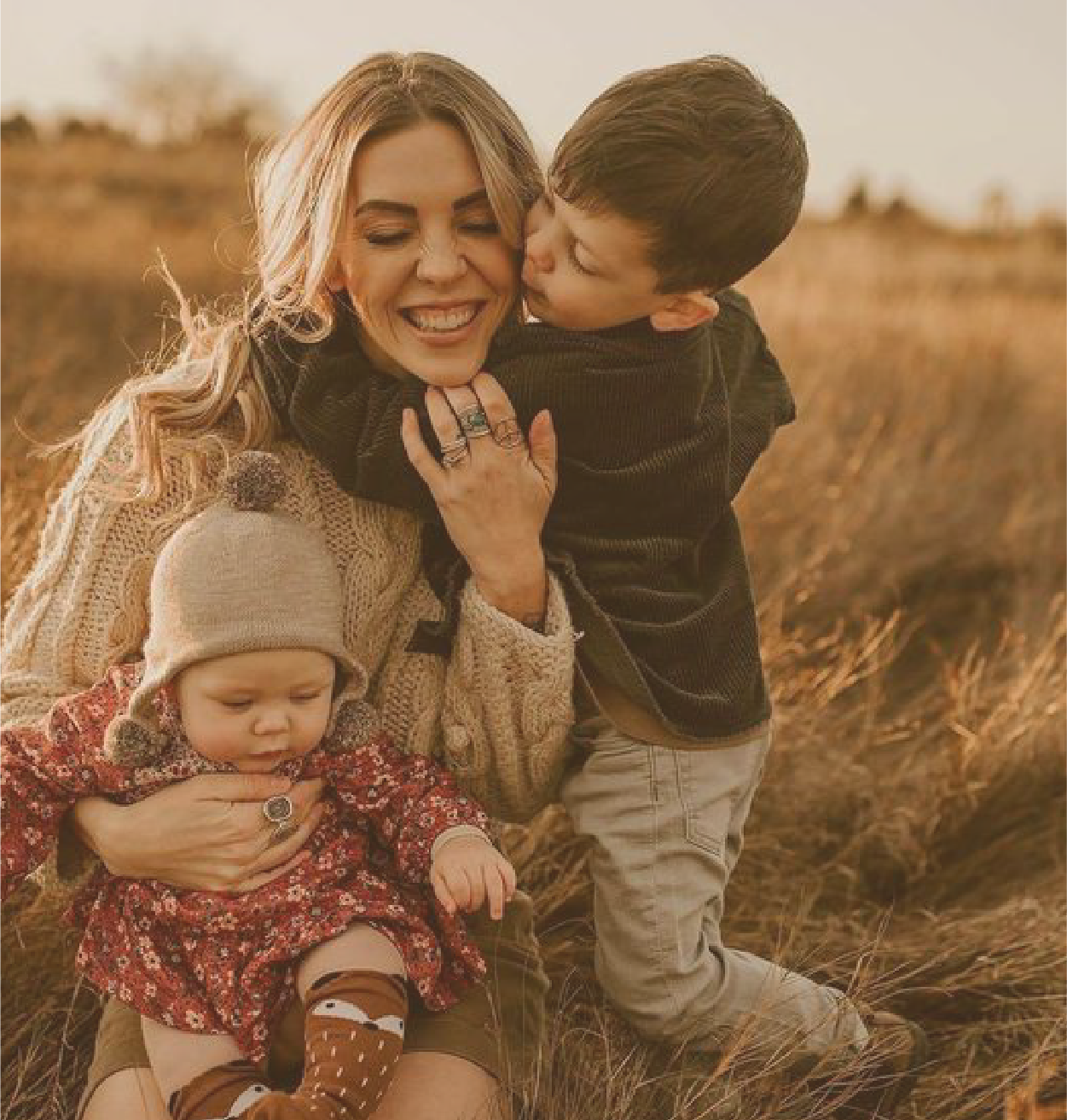 Mère et ses deux enfants souriants dans un champ