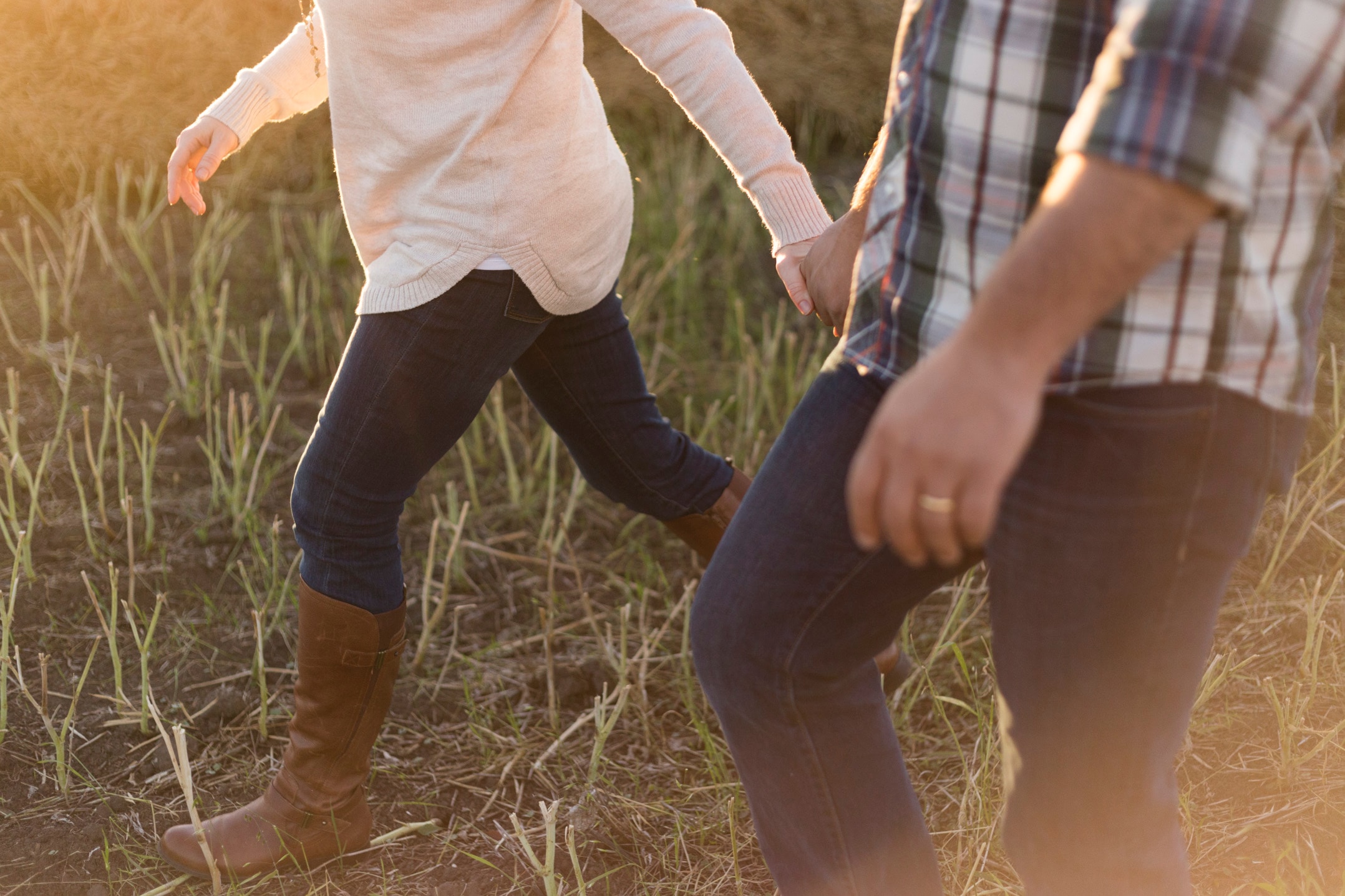 Un couple se tenant la main, marchant dans un champ